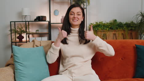 happy young woman looking approvingly at camera showing thumbs up, like positive sign, good news