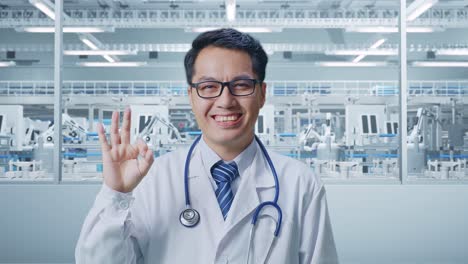 Doctor Smiling and Gesturing OK in a Modern Factory Setting