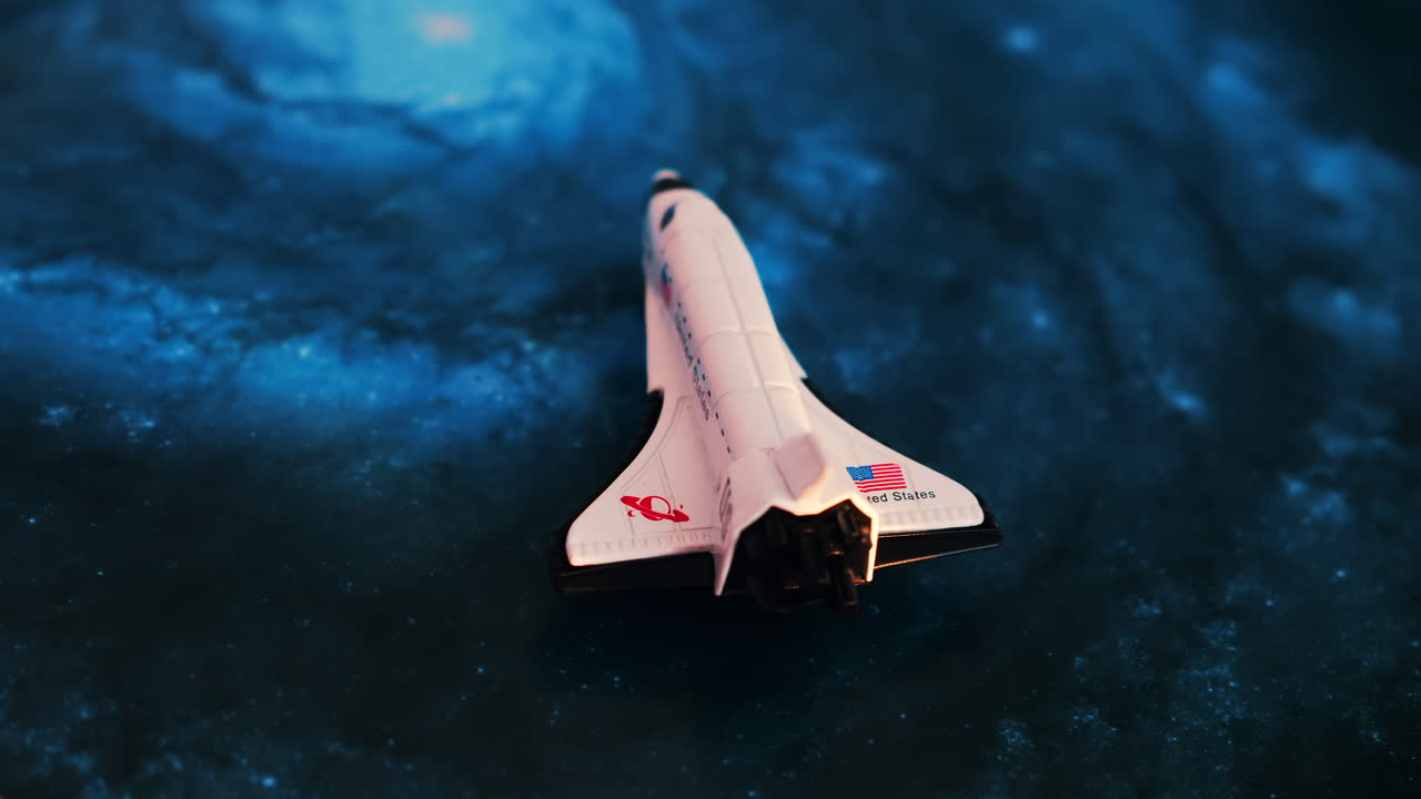 Close up of a miniature toy space shuttle placed on a blue cosmic galaxy backdrop