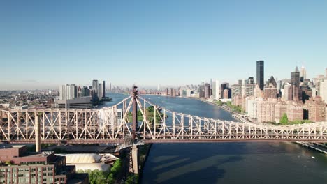 Long-aerial-of-industrial-looking-Queensboro-Bridge,-gorgeous-Manhattan-skyline-in-distance