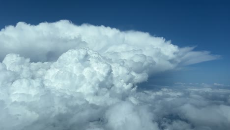 awesome view from a jet cabin of a huge threatening cumulonimbus storm cloud with a deep blue sky