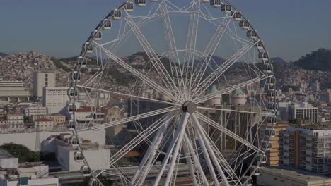 a large white ferris wheel dominates a city skyline with distant hills under a clear sky