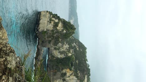 dolly vertical hacia adelante revela una toma de la playa de diamantes en nusa penida, bali, desde los acantilados de arriba revelando una playa de arena blanca y olas lentas