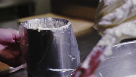 chef putting frosting in bowl