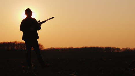 Silhouette-Eines-Jägers-Mit-Einer-Waffe,-Die-Sonnenstrahlen-Leuchten-In-Seinem-Gesicht