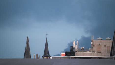 light fades as smoke blows over roofs in antwerp, belgium