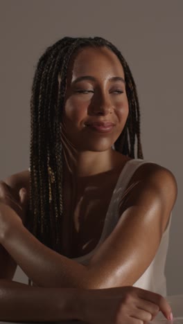 studio beauty shot of smiling young woman with long braided hair against neutral background 4