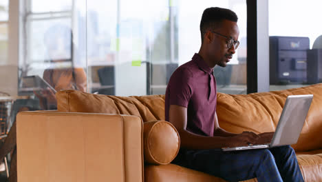 male executive using laptop on sofa 4k