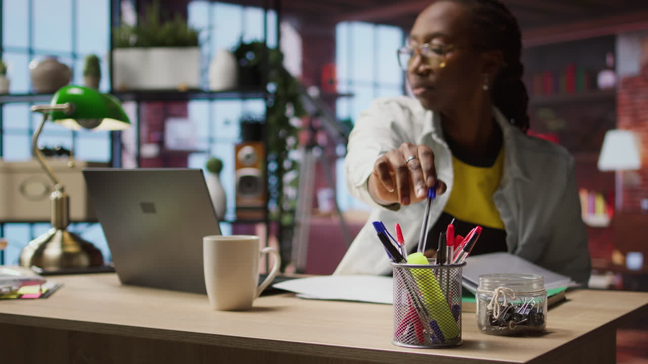 Bookkeeper in home office reading reports on laptop, taking notes