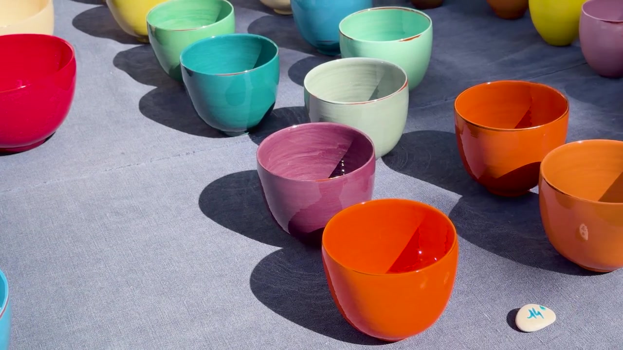 La telecamera si muove su vivaci ciotole di ceramica artigianale su un panno blu sotto la luce solare intensa.