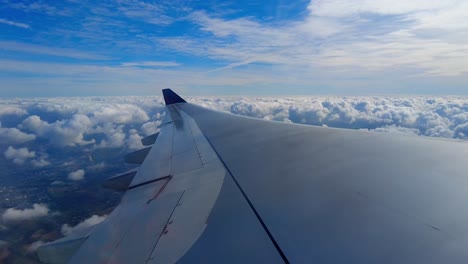 aircraft window view of airplane wing and beautiful clouds and landscape in background