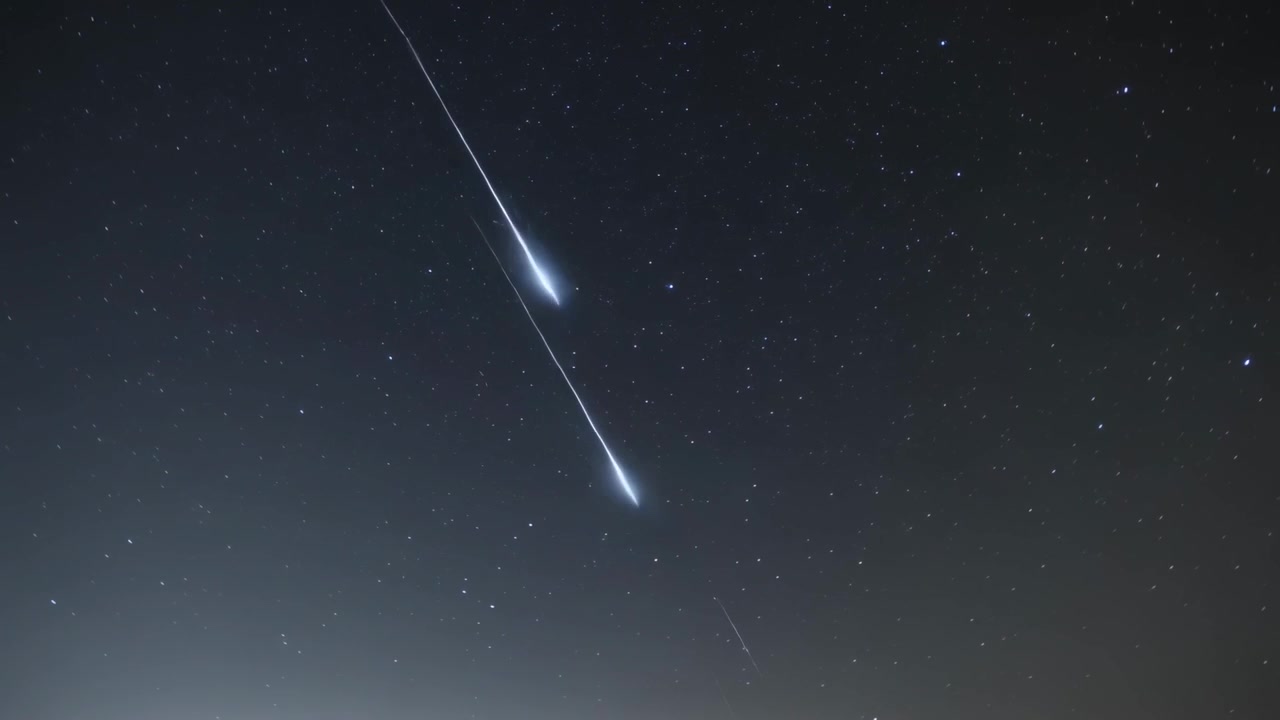 Lys stribe vises, meteor trænger ind i atmosfæren og fragmenterer over stjernefelt, efterlader et spor