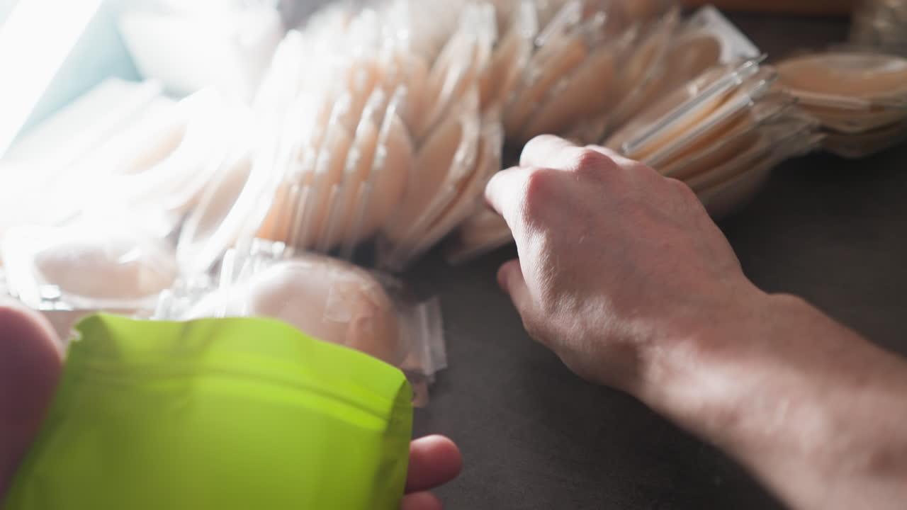 한 사람이 테이블에서 꼭지 파티를 선택하고 시장에서 판매하기 위해 지프 가방에 포장하는 pov