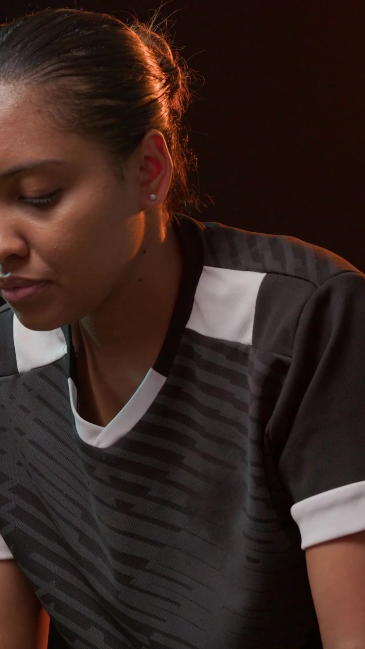 Video verticale: Donna in maglia, in studio, tiene un pallone da calcio all'altezza delle ginocchia, lo fa girare, mentre si riscalda.