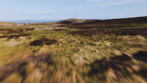 Aerial---flying-low-over-landscape-toward-radio-tower