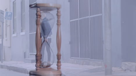 animación de reloj de arena sobre mujer de negocios biracial con hijab y caminando por la ciudad