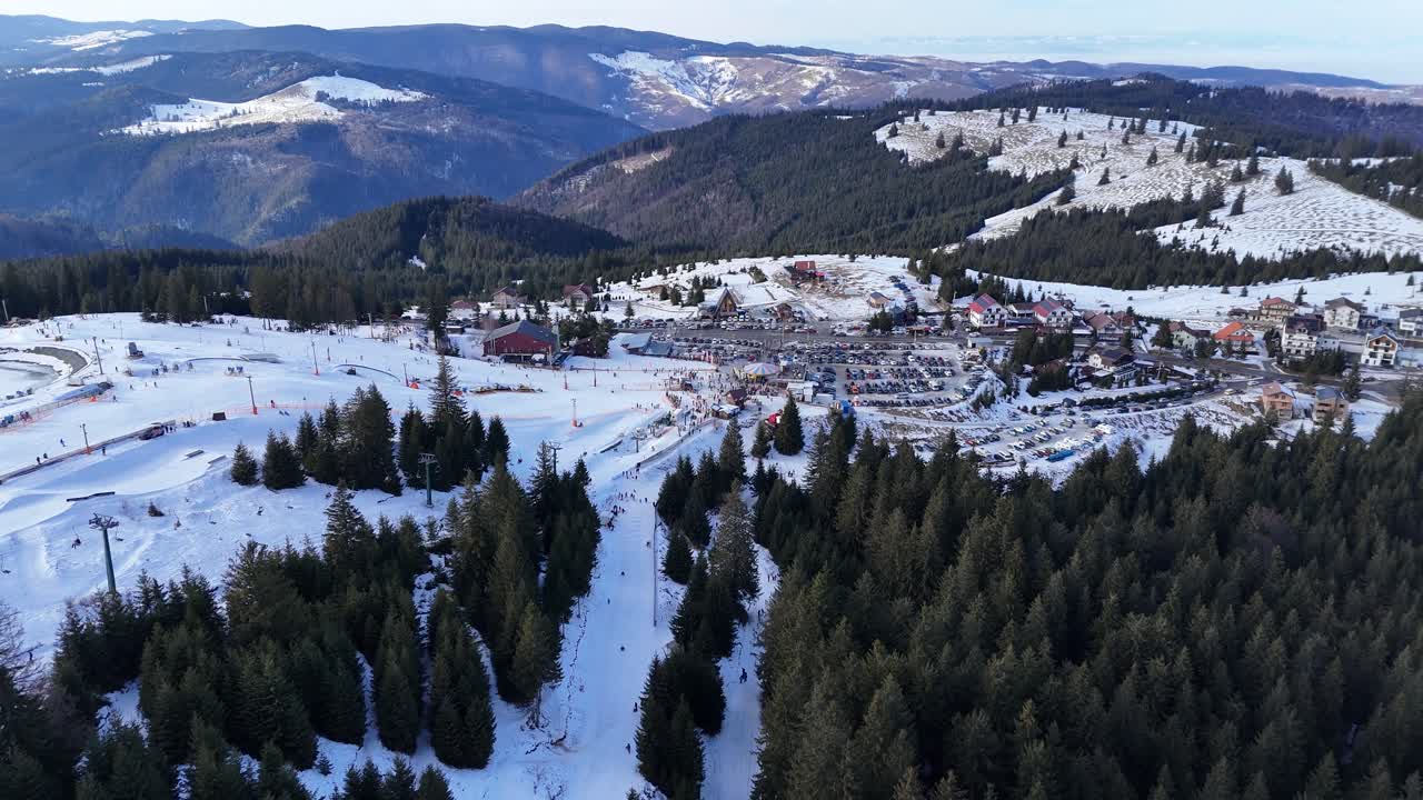 Filmato aereo con drone di una stazione sciistica innevata in montagna con persone che sciano in una giornata invernale. Concetto di sport invernali, turismo e attività ricreative all'aperto.