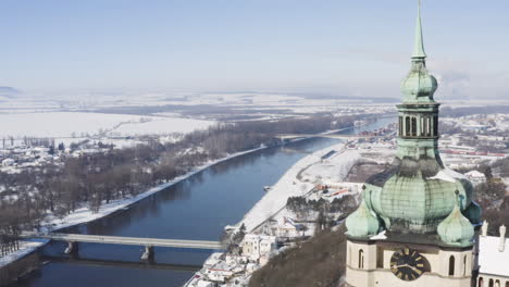 church clocktower overlooking a riverside town bridge,winter snow