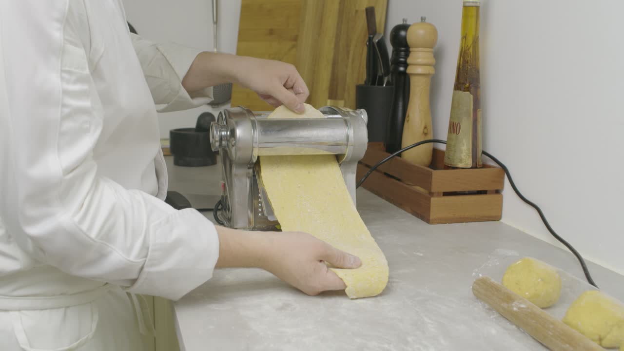 Far passare l'impasto della pasta attraverso una macchina per la pasta. Primo piano
