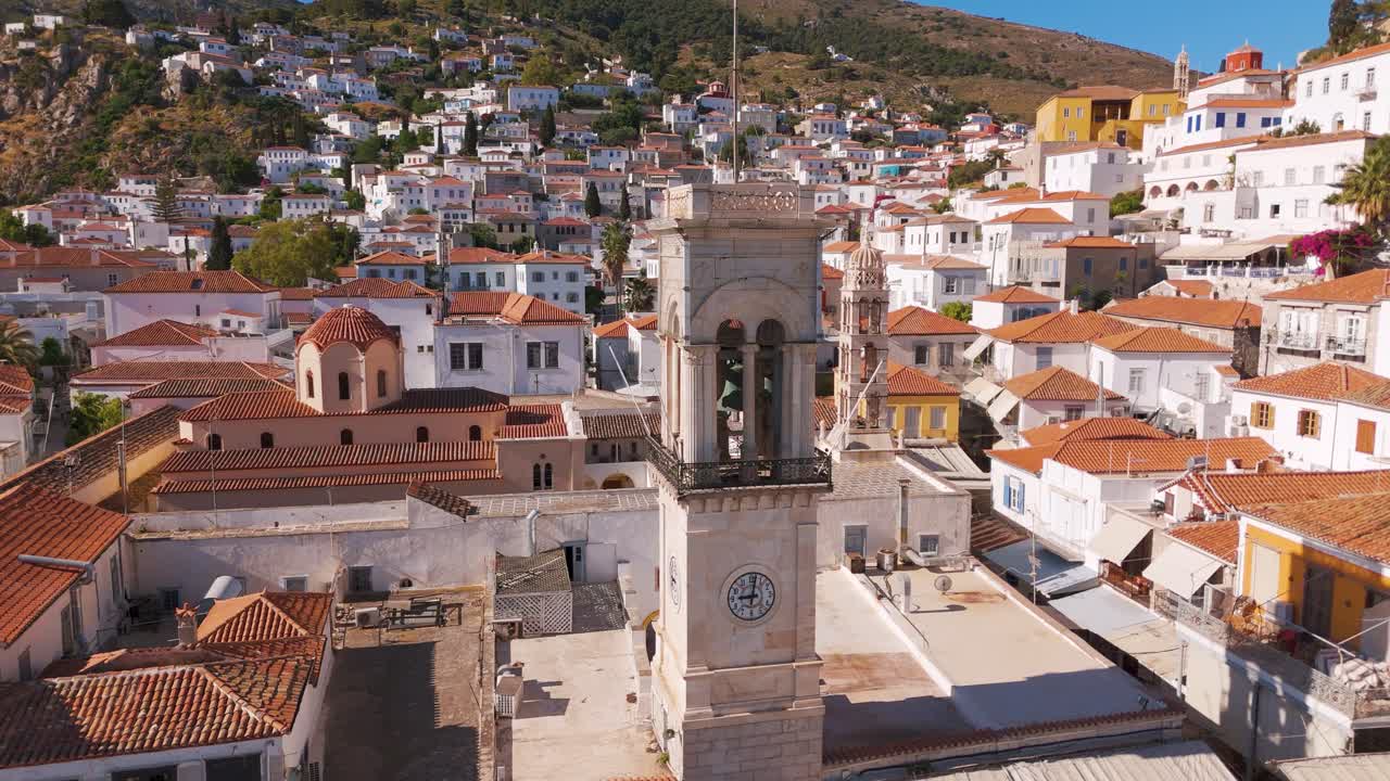Suggestiva vista aerea della città di Idra con la torre dell'orologio nella calda luce del pomeriggio.