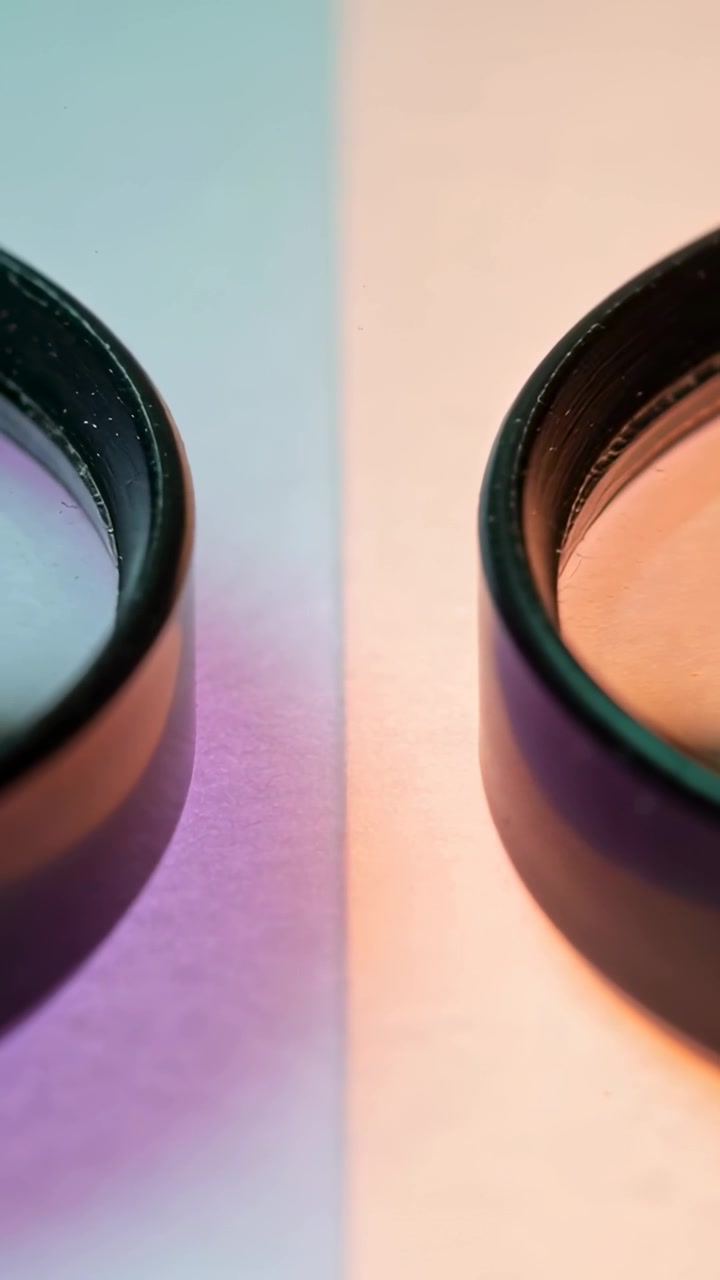 Vertical video: Moving cam pulling two black-rim lenses in on two-tone paper to show glare, dust