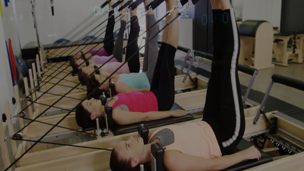 group of women performing reformer leg raises in fitness studio, with animated heart rate icon