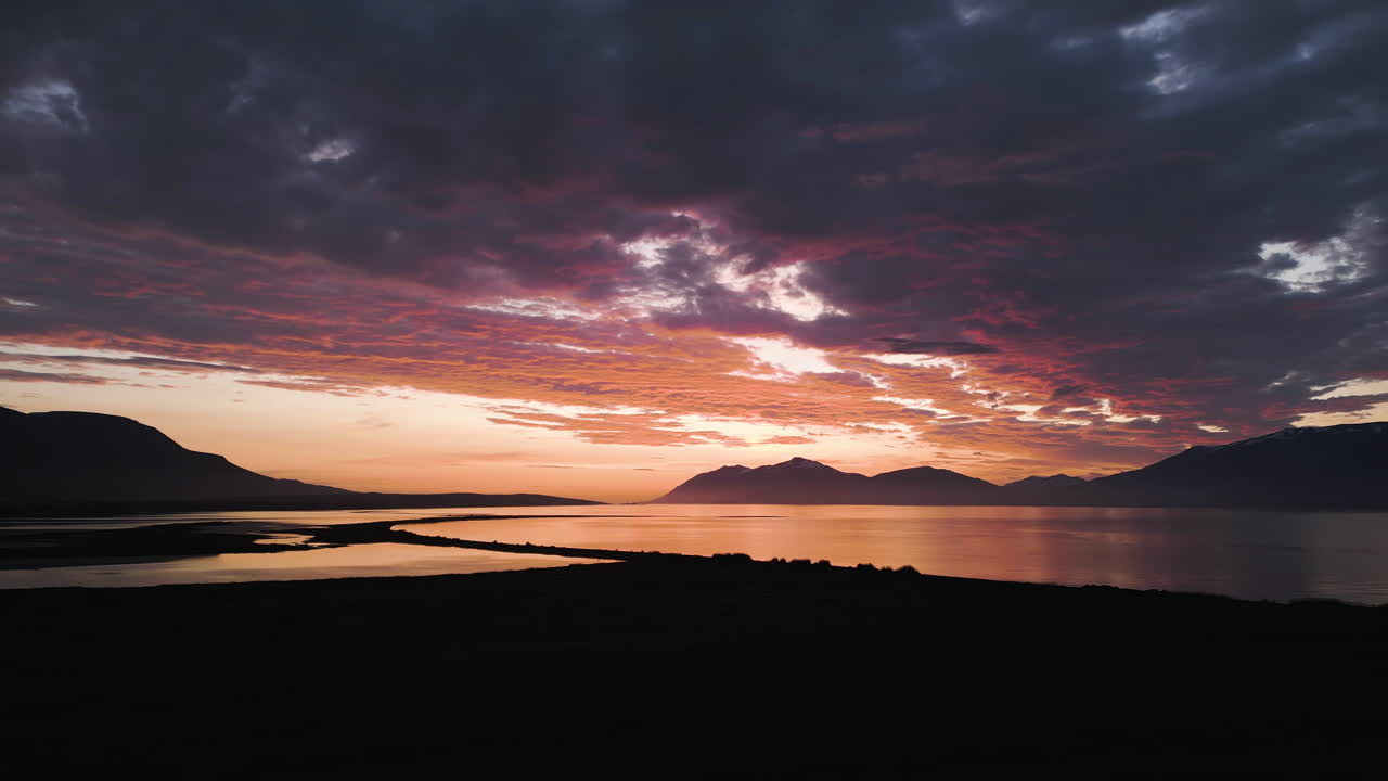 Amazing panning drone fly of glowing sunset over coastal Eyjafjordur fjord, Northern Iceland