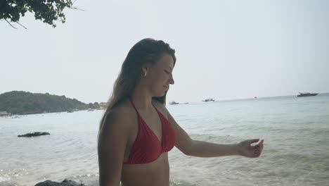 mujer feliz camina a lo largo de la costa contra las olas y el sol