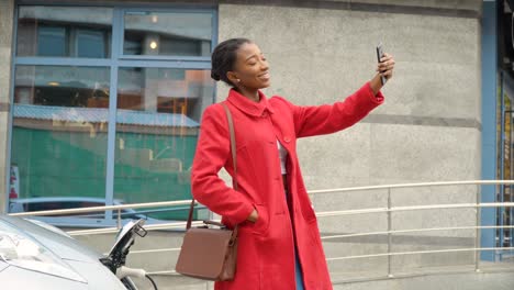 african american girl taking selfie with electric car that is charging. electrical car recharging. environmentally friendly transport