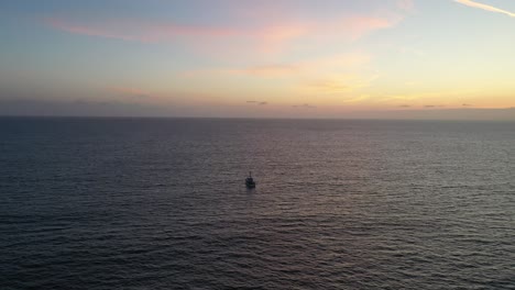 Boat-Sailing-Across-The-Calm-Ocean-At-Sunset