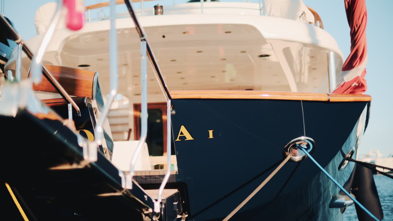 Rear angle of a luxury blue yacht with wooden details docked in a marina