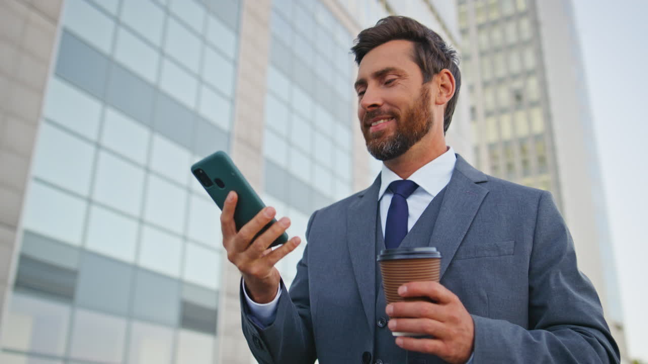 el gerente alegre termina la llamada caminando por la calle moderna con una taza de café de cerca.