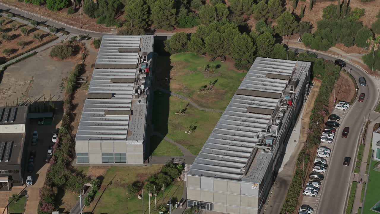 Aerial view of industrial warehouses with parked trucks and cars, showcasing modern architecture and logistics operations