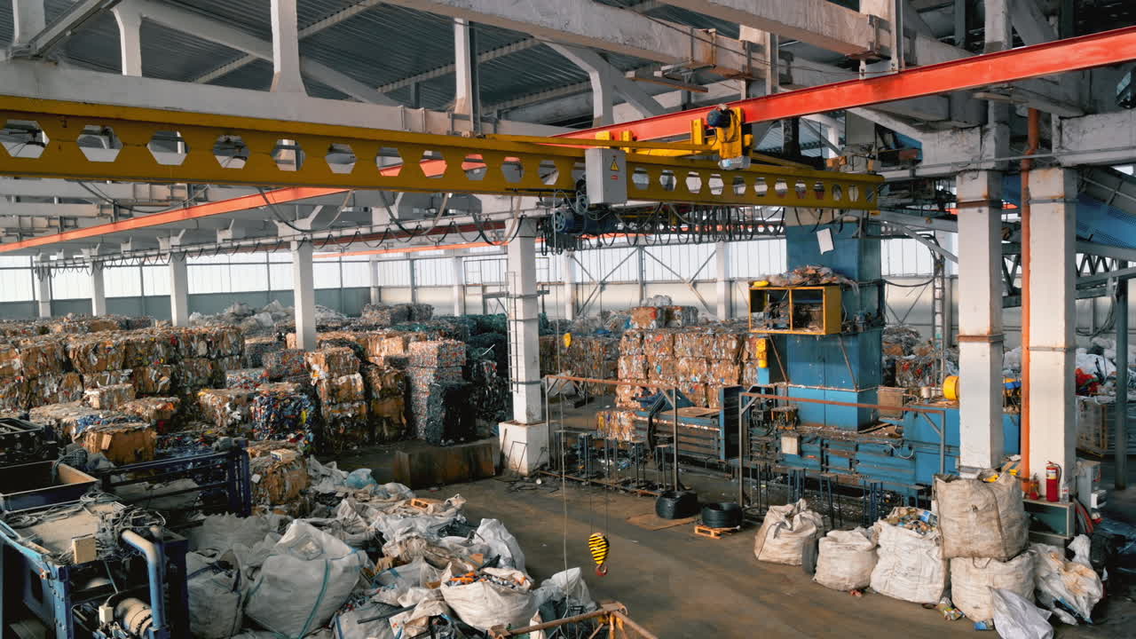 View of interior of a waste sorting plant. Cubes of compressed garbage, special tools, workers