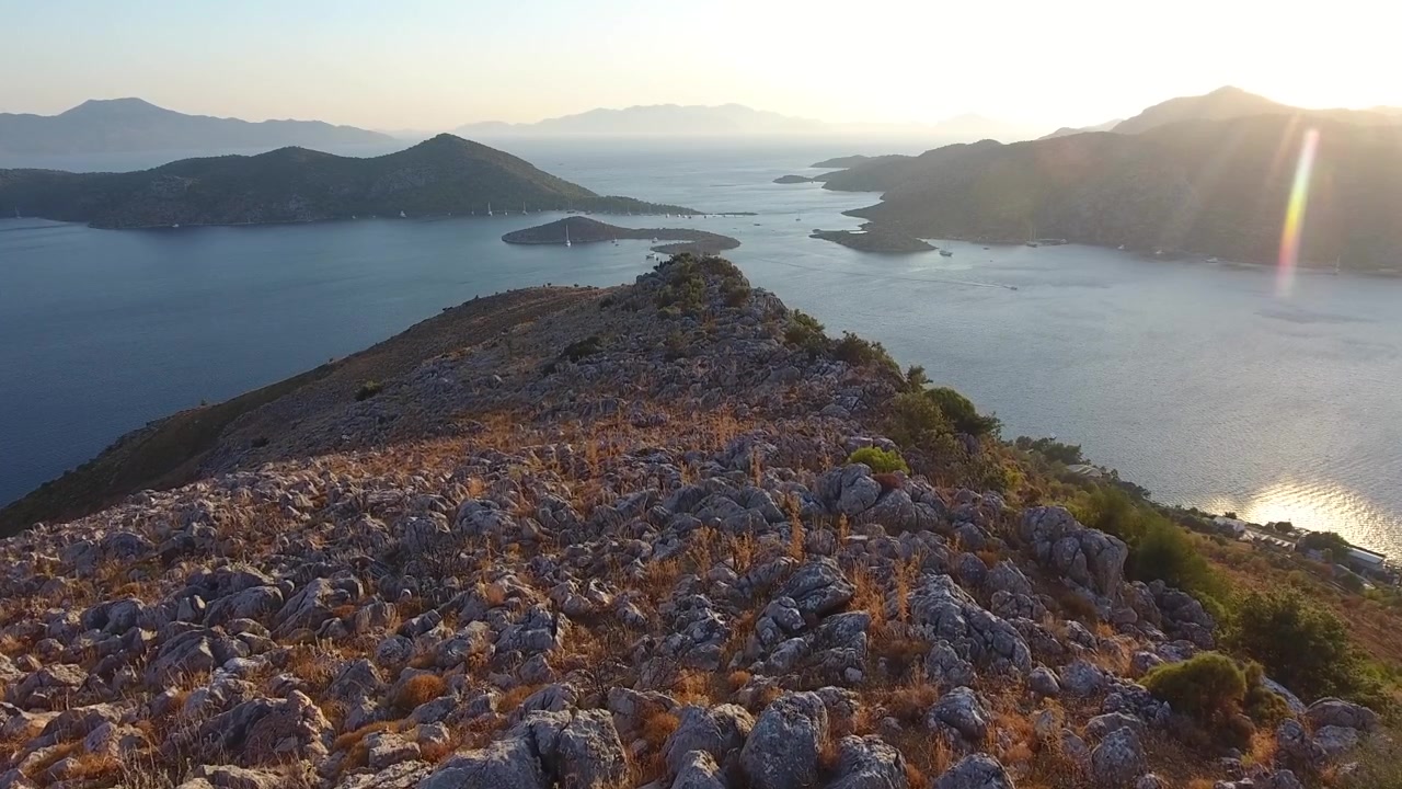 Vista Aérea de Crista Rochosa da Montanha com Vista para Baía Costeira ao Pôr do Sol
