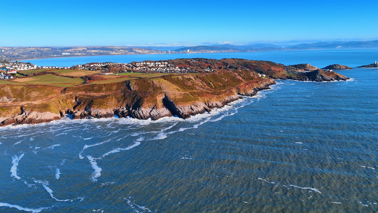 Vista aérea do promontório de Mumbles e da baía de Swansea, País de Gales. Ampla imagem de drone de cidade costeira, colinas verdes e ilhas rochosas no Canal de Bristol, País de Gales, Reino Unido