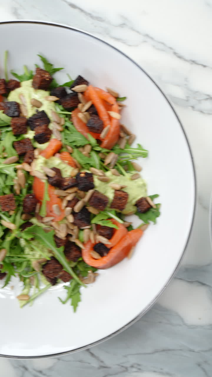 Vertical footage Chef preparing a greek salad with tomatoes, cucumbers, olives, feta, smoked salmon, avocado, croutons and seeds on a white background