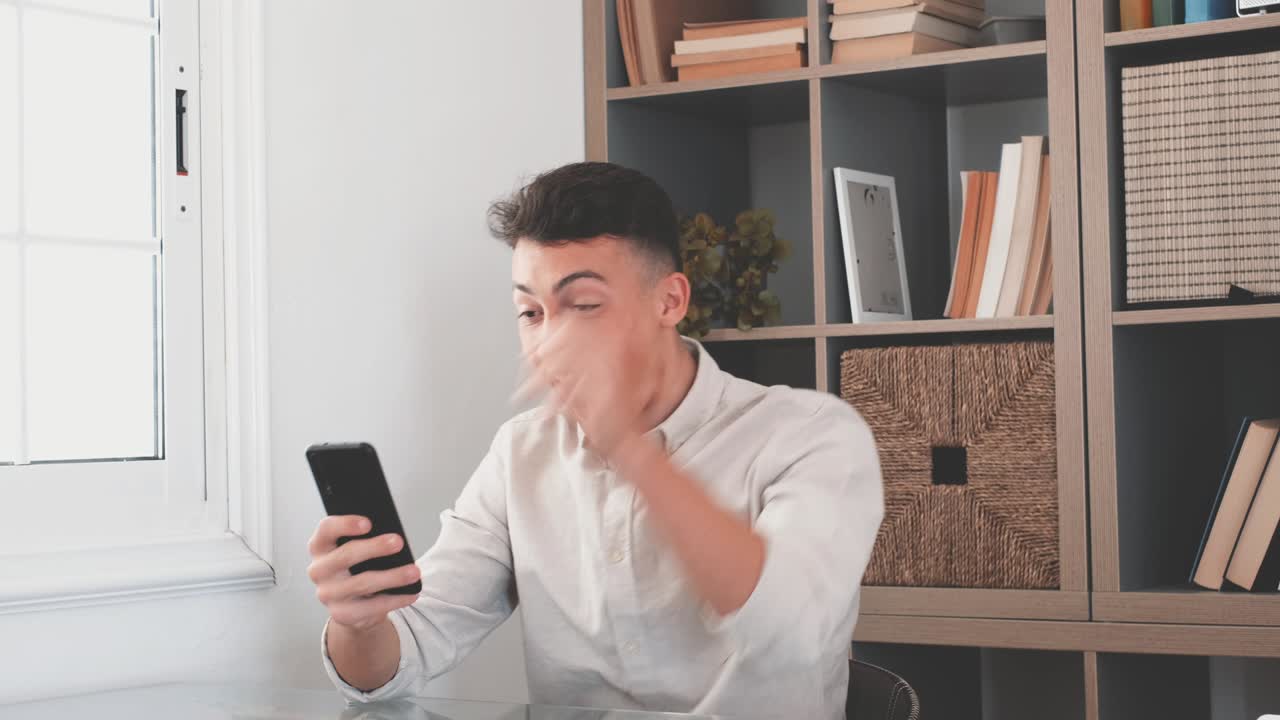 쾌락한 백인 인종 십대는 책상에 앉아 전화 화면을보고 믿을 수없는 뉴스를 읽습니다. 주먹을 고 '예' 제스처를합니다. 온라인 복권에서 축하합니다. 도박에서 승리합니다. 새로운 직업 제안을 받습니다.