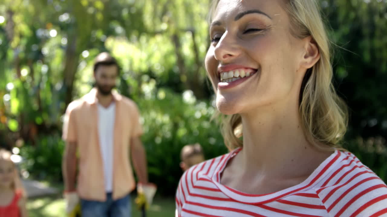 retrato de una madre feliz posando frente a su familia durante la jardinería