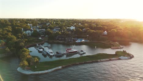 Vista-Aérea-De-Una-Lujosa-Zona-Residencial-Con-Yates-En-Un-Pequeño-Muelle-En-El-Río-Paraná,-Argentina.