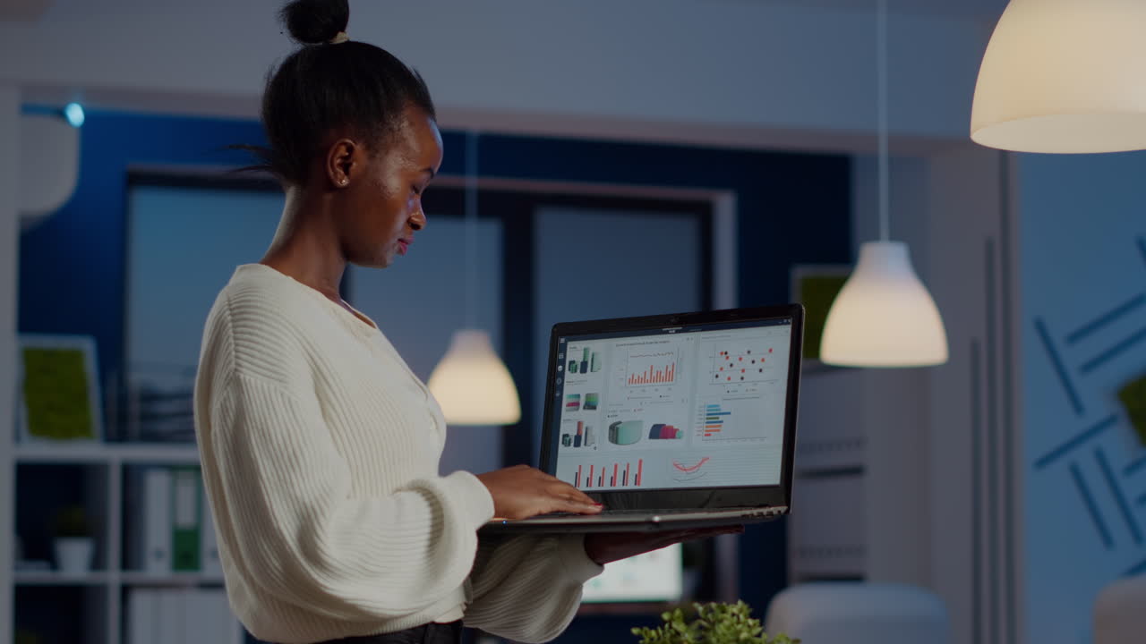 Focused black manager woman checking business report holding laptop