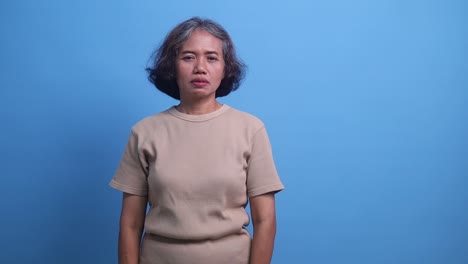 shocked amazed asian middle age woman standing while pointing sideways