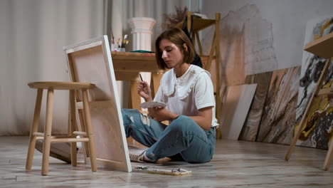 young woman sitting on the floor with canvas