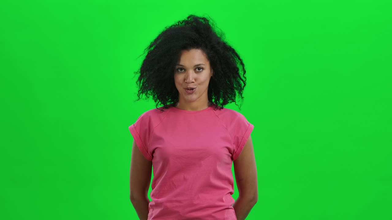 Portrait of young female African American nods her head and points not to do it with a gesture. Black woman with curly hair poses on green screen in the studio. Close up. Slow motion ready 59.97fps