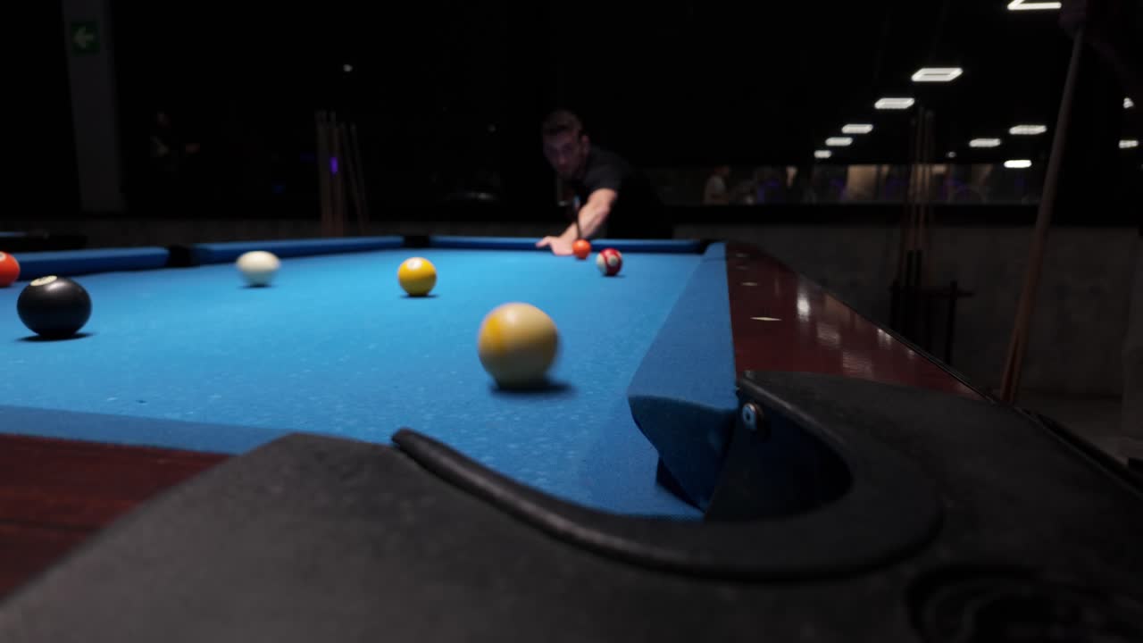 Uomo che gioca a biliardo in un bar buio