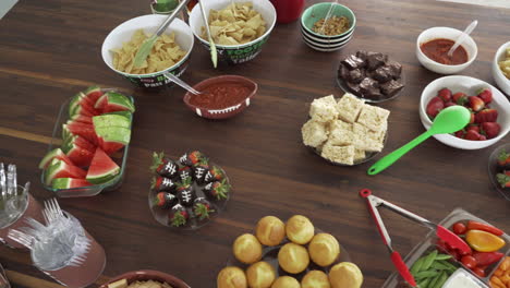 overhead pan of party smorgasbord of football theme snacks and food on table for super bowl