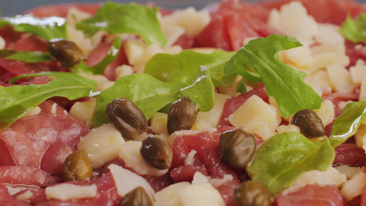 Primo piano di carpaccio di manzo con rucola, Parmigiano e capperi