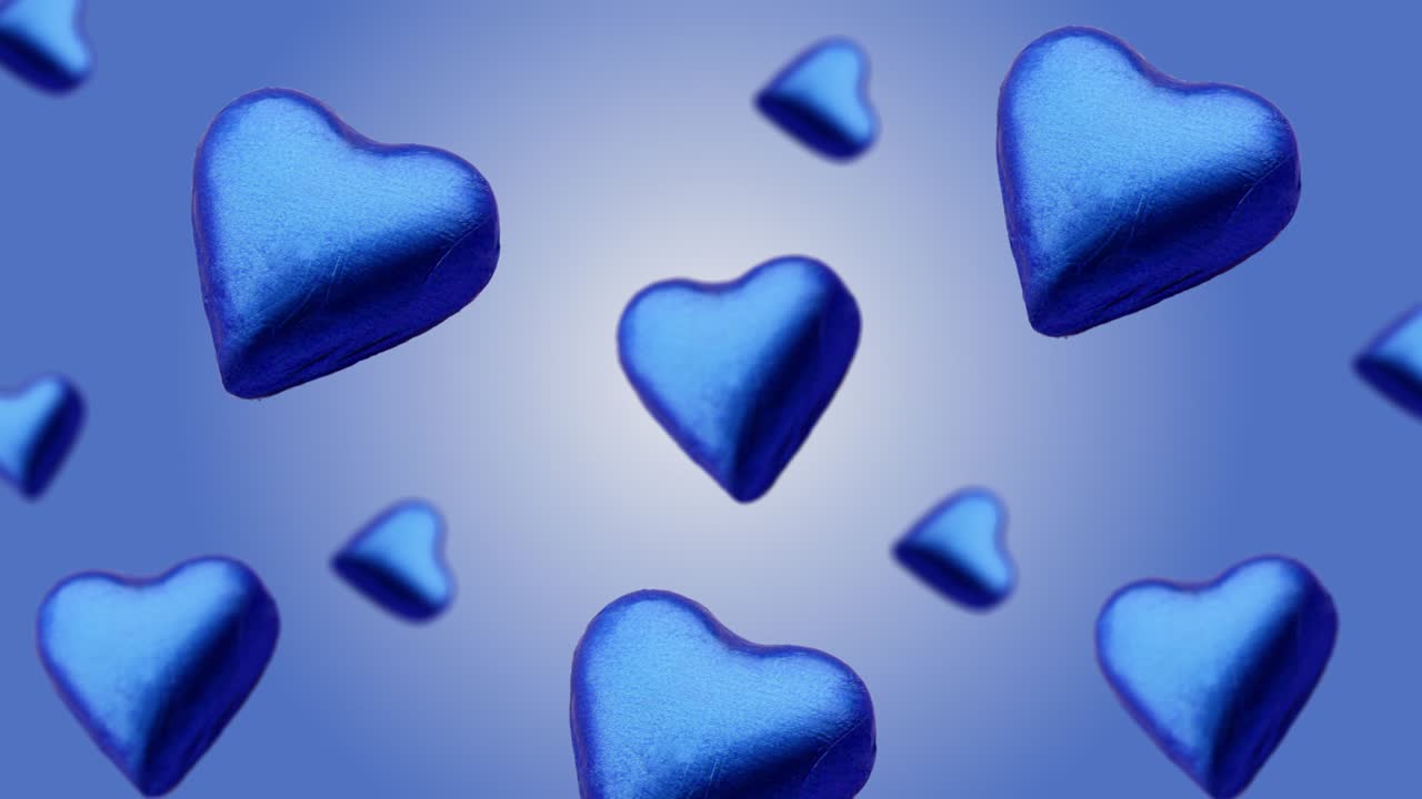 심장 모양으로 포장 된 초콜릿 사탕이 파란색 그라디언트 배경에서 다른 지름의 날아가고 흔들립니다. 고품질 4k uhd 영상