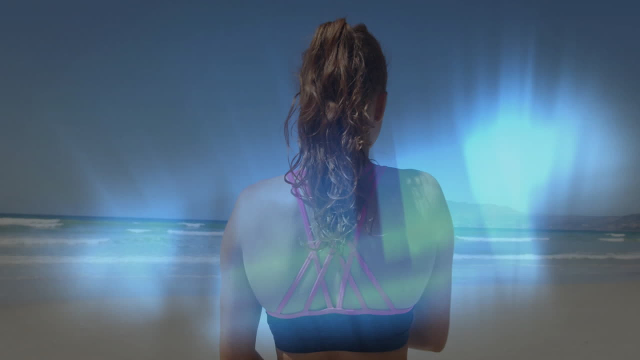 Facing ocean, woman in sportswear with glowing blue aura animation effect