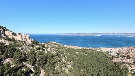 aerial view of marseille coastline and harbor with city rooftops and mediterranean sea under clear blue sky, seen from elevated hills in southern france